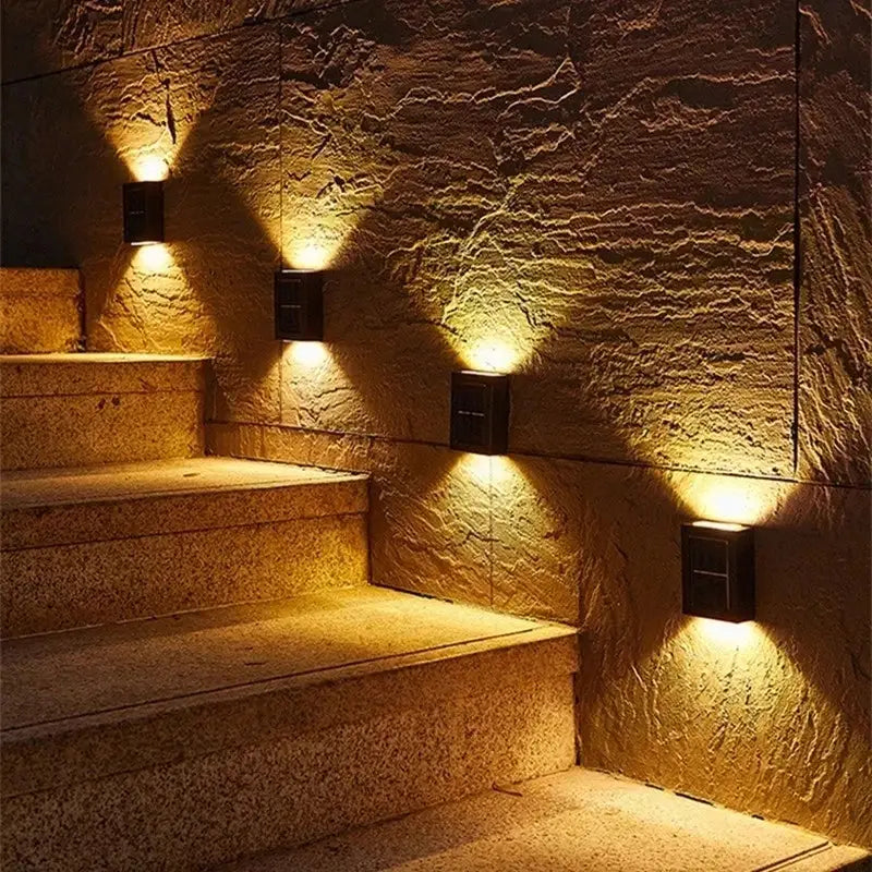 Black solar wall light by Decorbites; five outdoor fixtures with warm uplighting on stone wall on Tampa Home & Garden Store