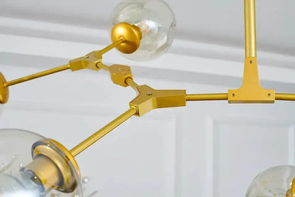 Modern glass chandelier with gold finish metal arms and clear globe bulbs on Tampa Home & Garden Store
