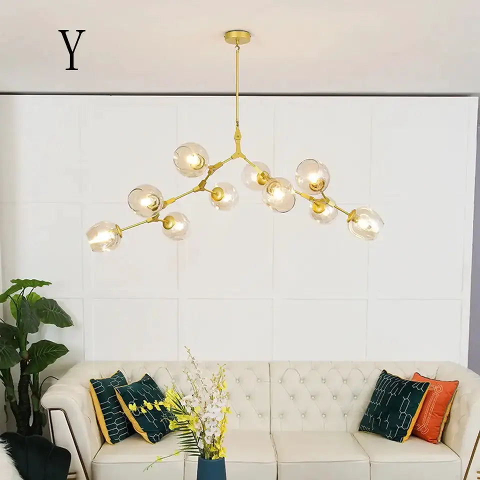 Chandelier Decorbites amber glass with gold arms and globe bulbs over a white tufted sofa on Tampa Home & Garden Store