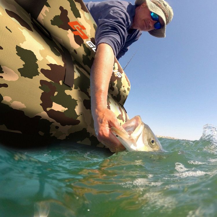 Mercantile Mountain camo inflatable fishing float tube in water with a fisherman holding a fish on Tampa Home & Garden Store