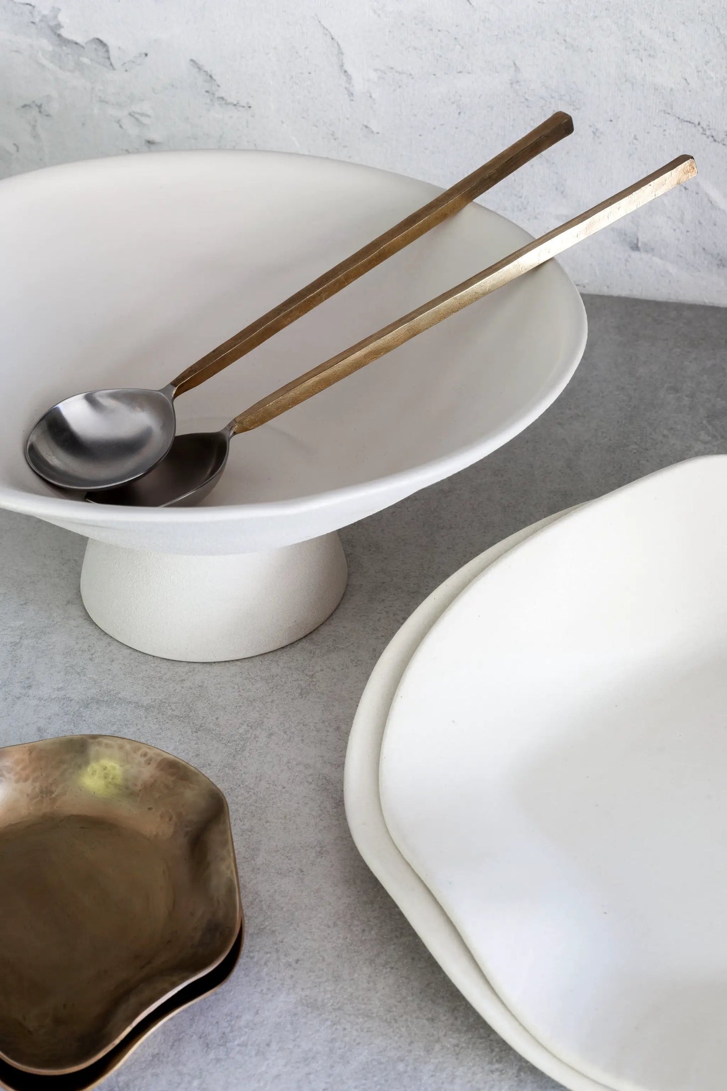 Sidney Servers two bronze-handled serving spoons on a white pedestal bowl by dumæ Serveware on Tampa Home & Garden Store