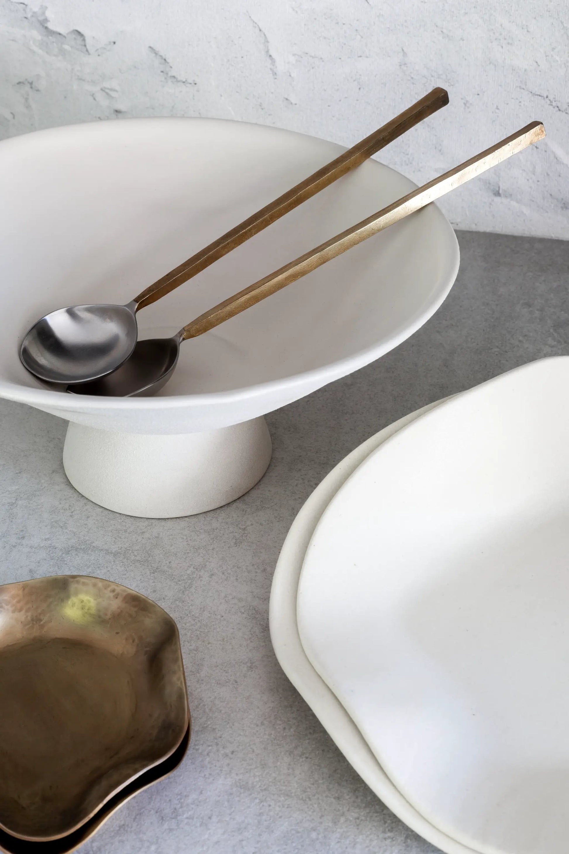 Sidney Servers two bronze-handled serving spoons on a white pedestal bowl by dumæ Serveware on Tampa Home & Garden Store