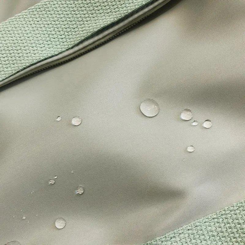 Laptop backpack fabric close-up in gray with water droplets and mint-green strap on Tampa Home & Garden Store