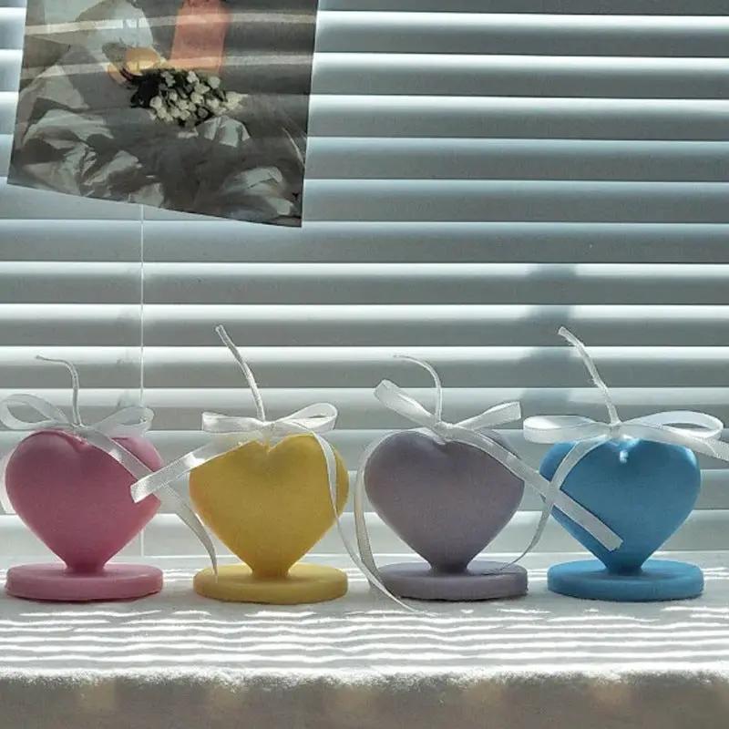 Four pastel heart-shaped candles with white ribbons on matching bases on Tampa Home & Garden Store