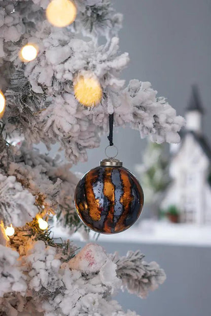 Christmas ball ornament with amber-brown and black stripes, hung on a snowy tree with lights on Tampa Home & Garden Store