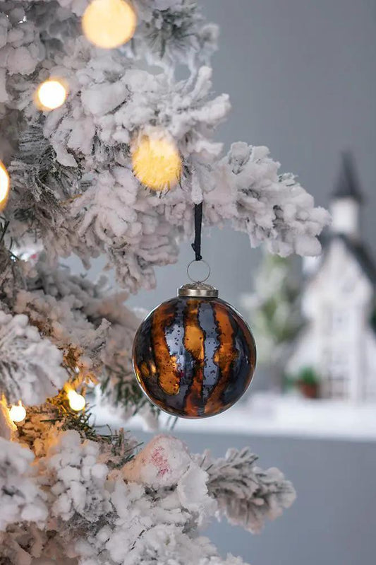 Christmas ball ornament with amber-brown and black stripes, hung on a snowy tree with lights on Tampa Home & Garden Store