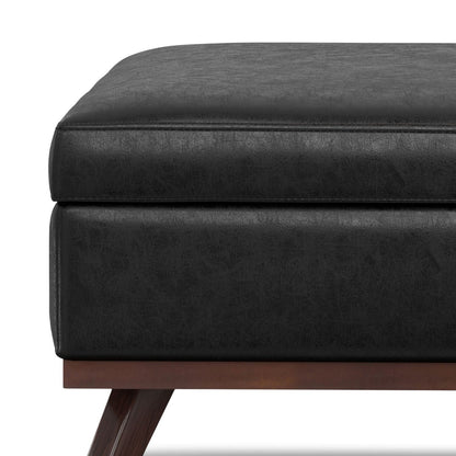 Square lift-top storage ottoman in black faux leather with brown wooden legs on Tampa Home & Garden Store