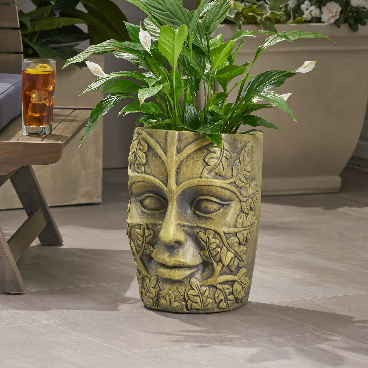 Garden urn planter with carved face, vine detail and weathered gold finish holding green plant on Tampa Home & Garden Store