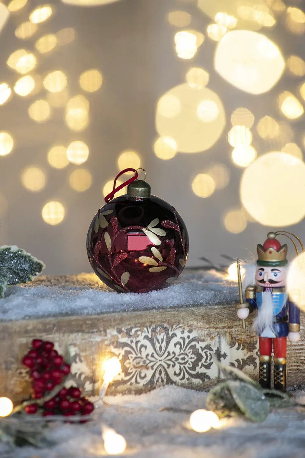 Glass burgundy Christmas ball ornament with gold leaf pattern, hanging on festive display on Tampa Home & Garden Store
