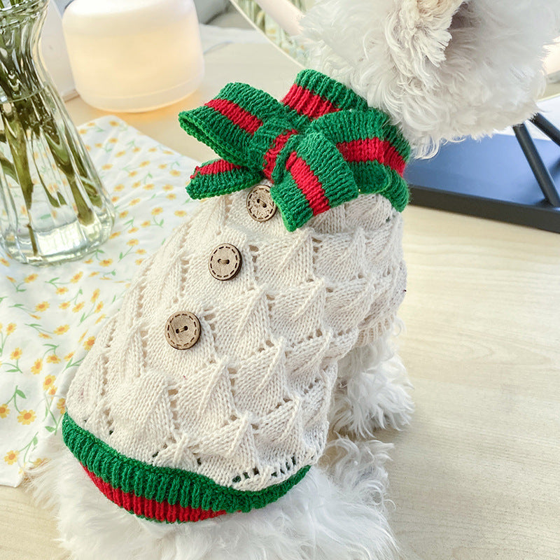 Bowknot hollow-knit dog sweater in cream with wooden buttons and green-red trim bow on a fluffy white dog on Tampa Home & Garden Store