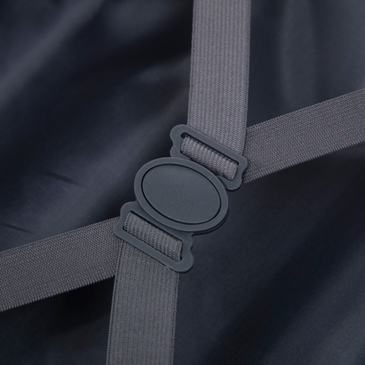 Luggage strap hardware with grey nylon webbing and ABS wheel housing on dark fabric background on Tampa Home & Garden Store