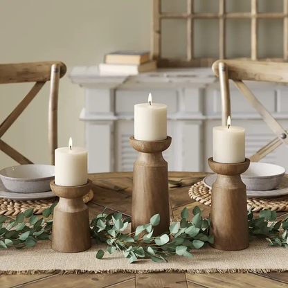 Solid wood retro candlestick trio with ivory pillar candles on a rustic dining table with greenery on Tampa Home & Garden Store