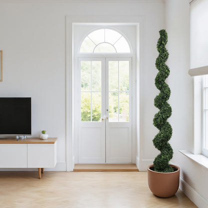 Faux spiral topiary plant in a terracotta pot beside a bright window in a minimalist living room on Tampa Home & Garden Store
