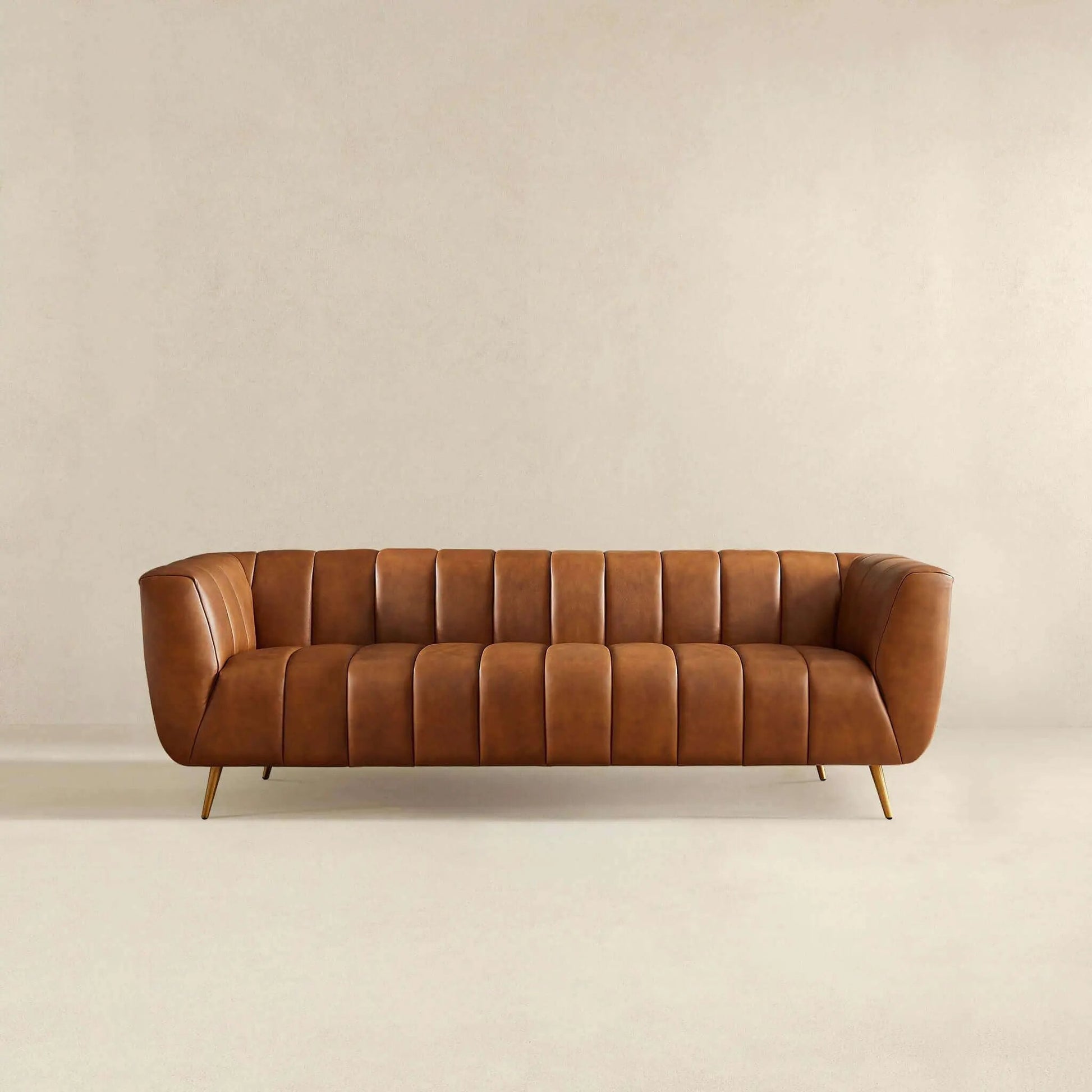 Ava sofa in gold tan leather with channel tufting and slender gold legs on Tampa Home & Garden Store