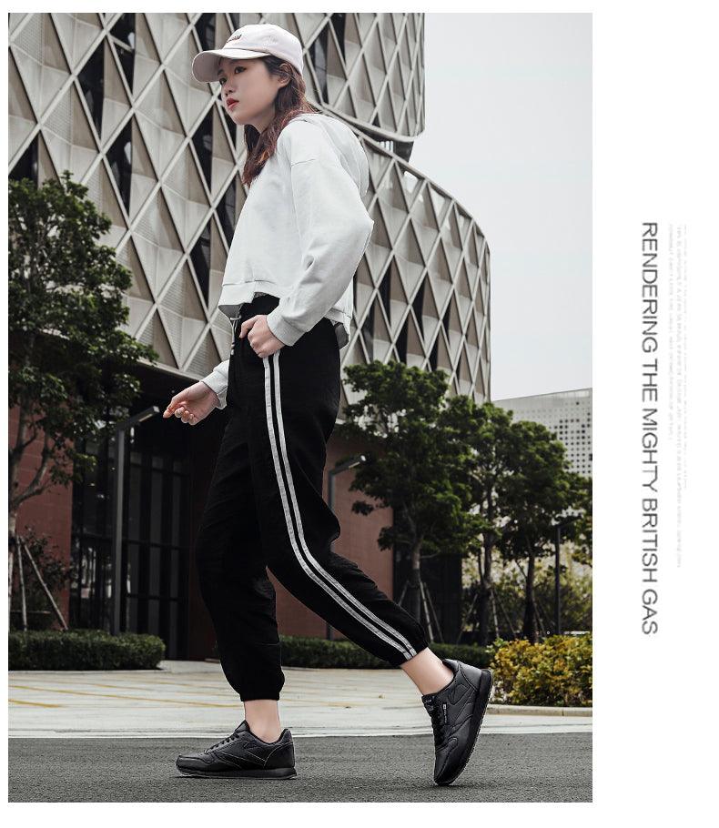 Stevvex black sneakers worn by a model in an urban street look with gray hoodie and striped joggers on Tampa Home & Garden Store