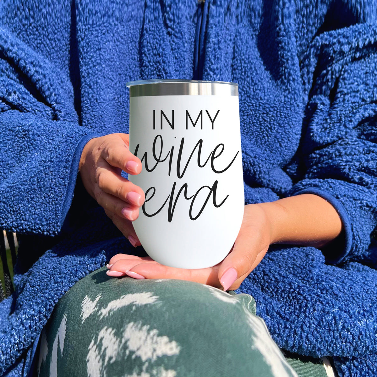 Wine Era 17oz tumbler, white with silver rim, held by hands in a blue fleece robe on Tampa Home & Garden Store