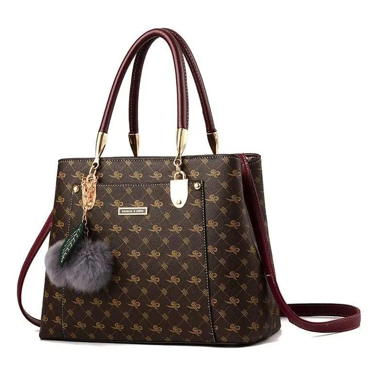 Stevvex brown monogram satchel bag with burgundy handles and gold hardware, furry pom charm on Tampa Home & Garden Store