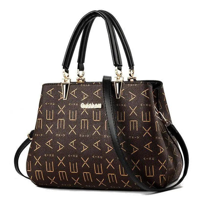 Stevvex brown leather satchel with black top handles, gold hardware, and geometric logo plate on Tampa Home & Garden Store