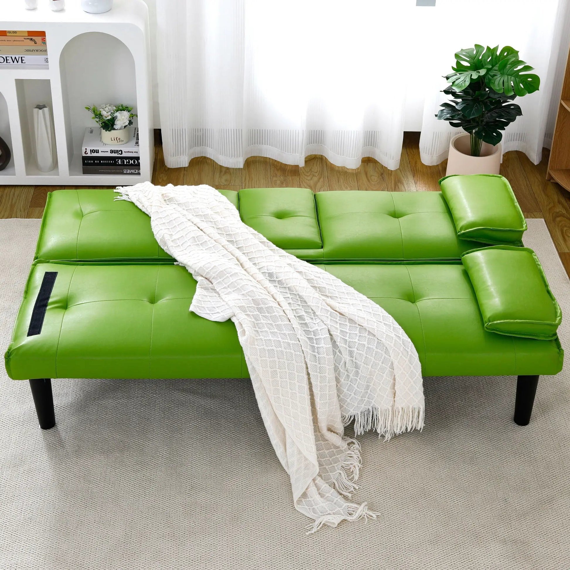 Green leather futon sofa bed with tufted cushions in a bright living room on Tampa Home & Garden Store