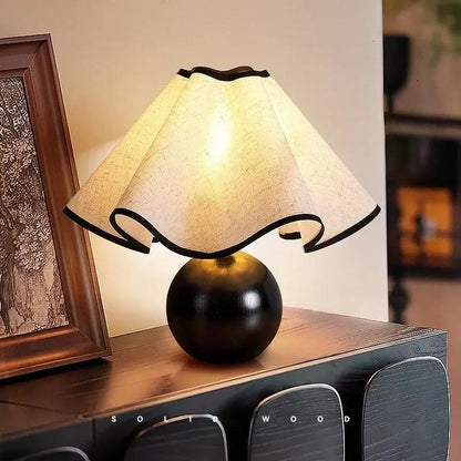 Table lamp with walnut-toned spherical base and cream petal shade with black trim on Tampa Home & Garden Store