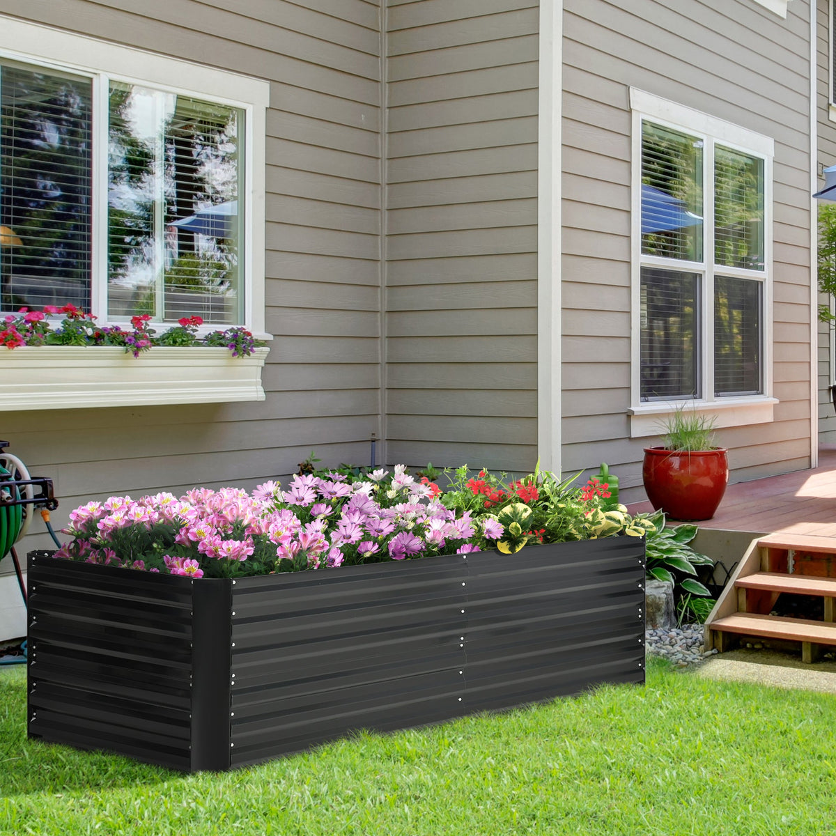 Galvanized black raised garden bed, planted with pink flowers near windows on Tampa Home & Garden Store