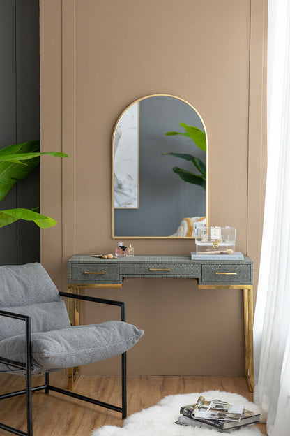 Arched wall mirror with slim gold metal frame above a grey textured console with gold legs on Tampa Home & Garden Store