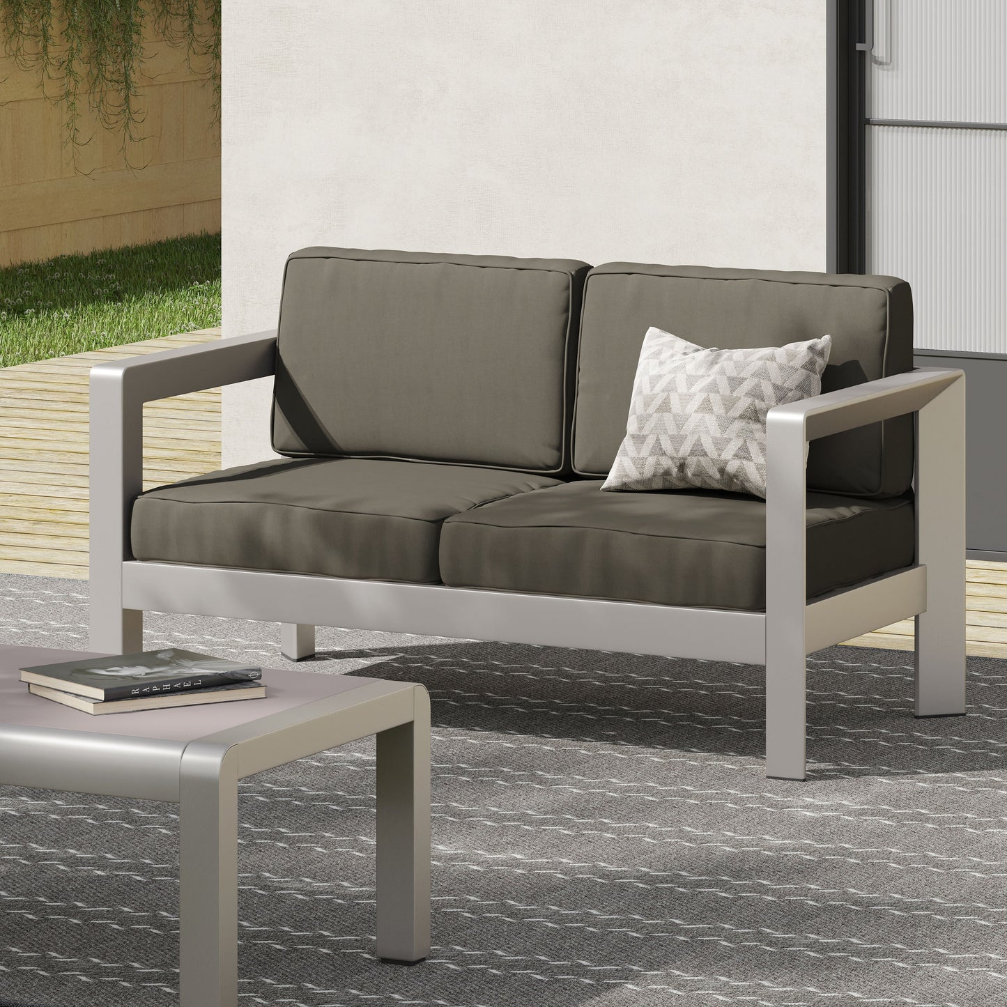Outdoor aluminum loveseat with deep gray cushions in a low-profile patio setup on Tampa Home & Garden Store