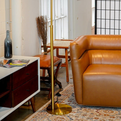 Elara Floor Lamp Gold by HouseOfZazla in a modern living room beside a tan leather sofa on Tampa Home & Garden Store