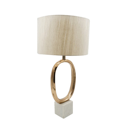 Table lamp with gold-tone oval metal base and cream linen shade on a marble square pedestal on Tampa Home & Garden Store
