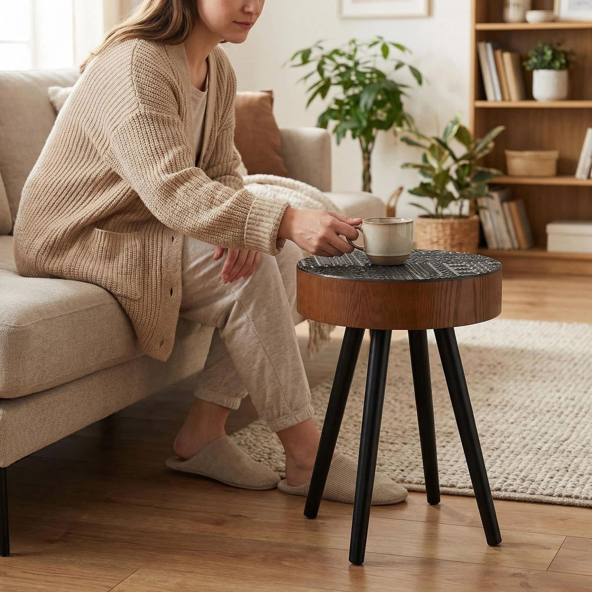 Round carved-top coffee table with dark brown wood top and black legs in living room on Tampa Home & Garden Store