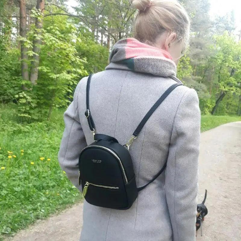 Stevvex mini soft-touch leather backpack, black, worn by a woman in a coat on a park path on Tampa Home & Garden Store