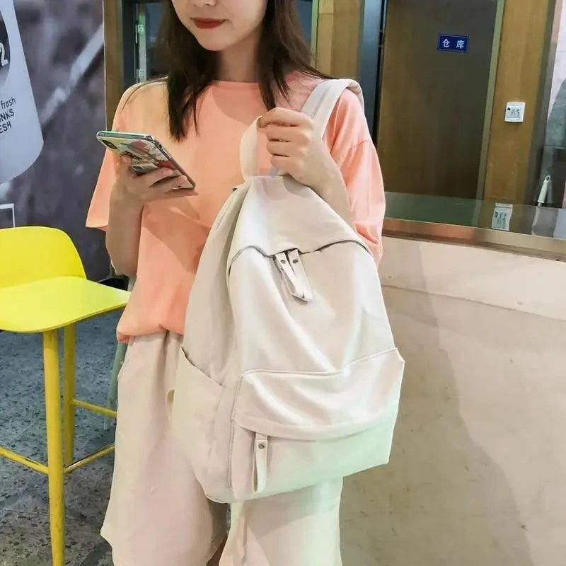 Beige anti-theft laptop backpack for teens with front pocket carried by girl in peach top on Tampa Home & Garden Store