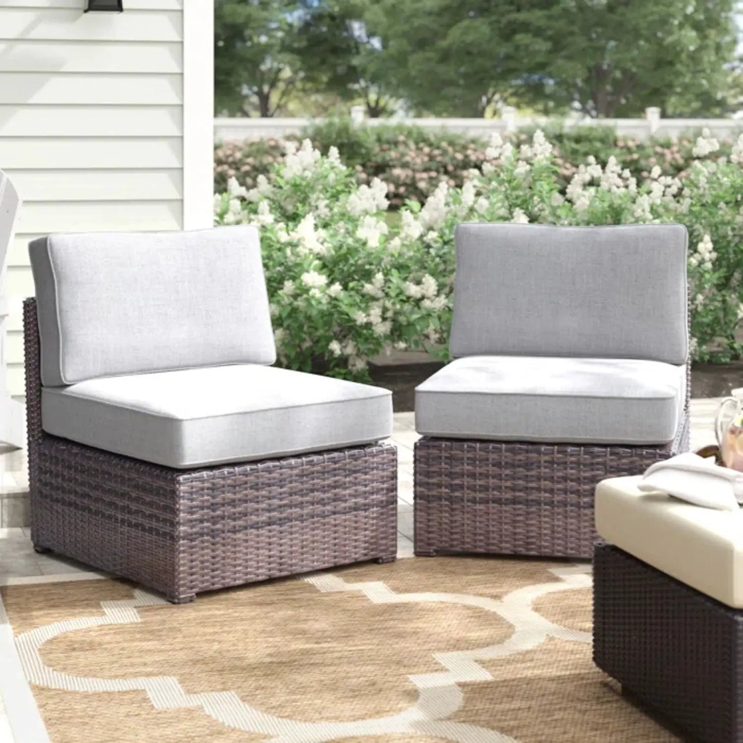 2 armless patio chairs with light gray cushions in brown wicker frames on Tampa Home & Garden Store