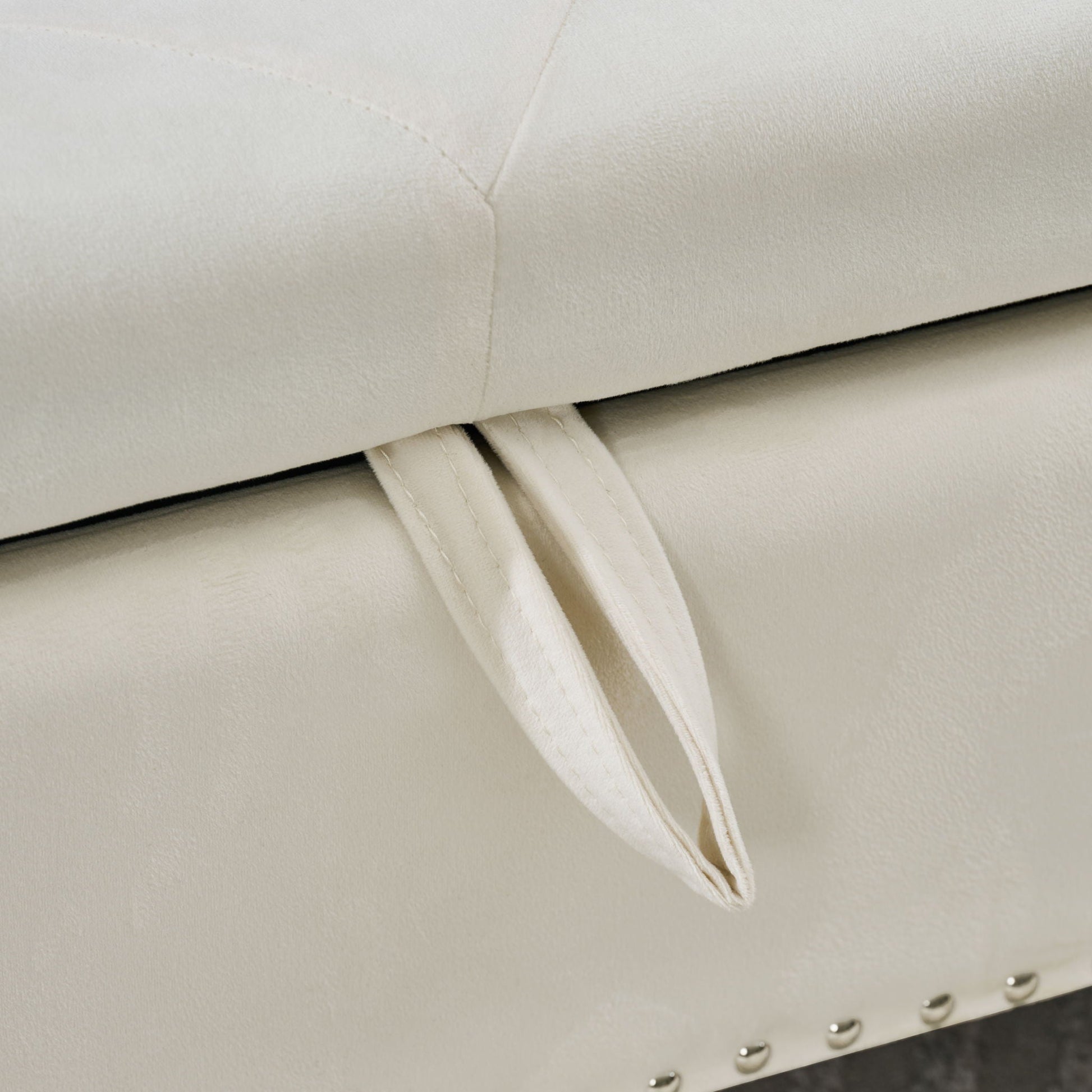 Storage bench upholstered in cream fabric with tufted lid and metal studded trim on Tampa Home & Garden Store