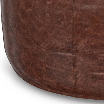 Handcrafted round leather pouf in distressed brown with stitched panel seams on Tampa Home & Garden Store