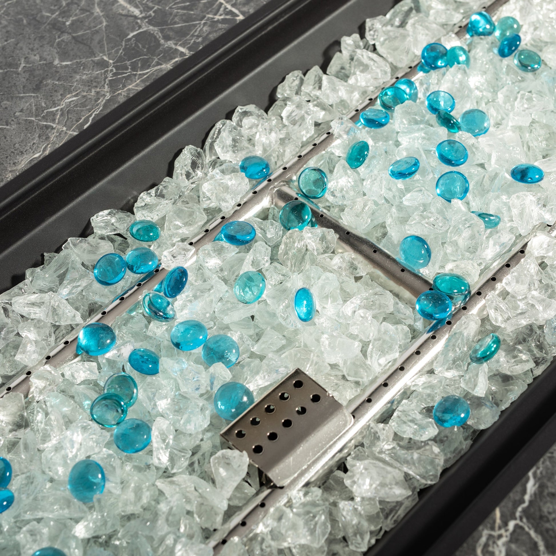 Gas fire pit interior with teal glass beads and crushed ice, perforated burner rail on Tampa Home & Garden Store