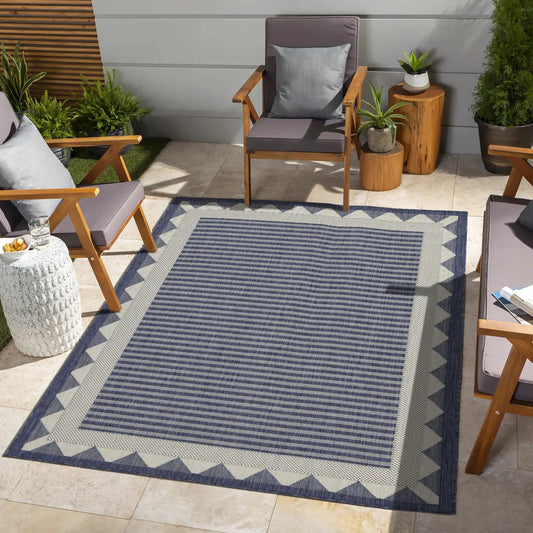 Sunshine Area Rug by Unique Piece Furniture, navy blue with striped center and light gray border on outdoor patio on Tampa Home & Garden Store