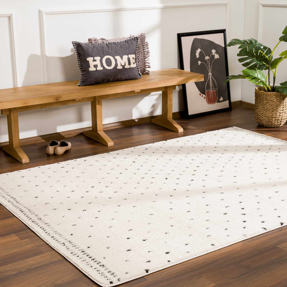 Julie Area Rug white with black dot edging on dark wood floor beside a bench and plant on Tampa Home & Garden Store