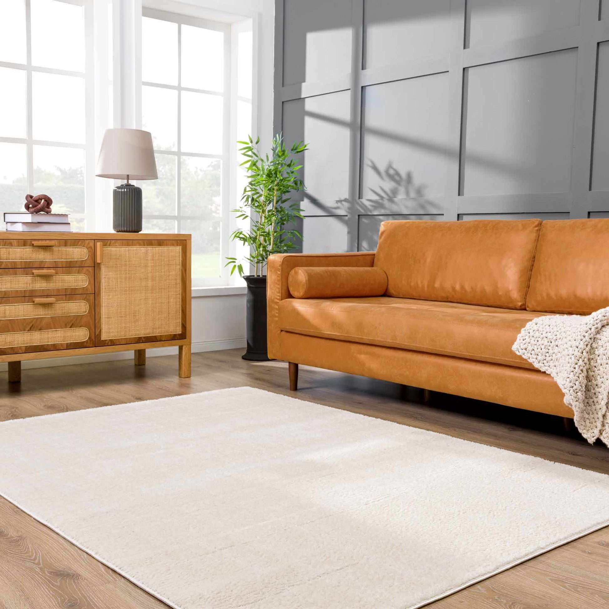 Koume Ivory Area Rug by Boutique Rugs, cream woven rug in a living room with a tan leather sofa on Tampa Home & Garden Store