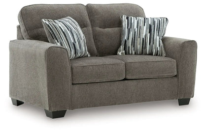 Olten stationary chair in taupe gray fabric with two striped pillows and dark block feet on Tampa Home & Garden Store