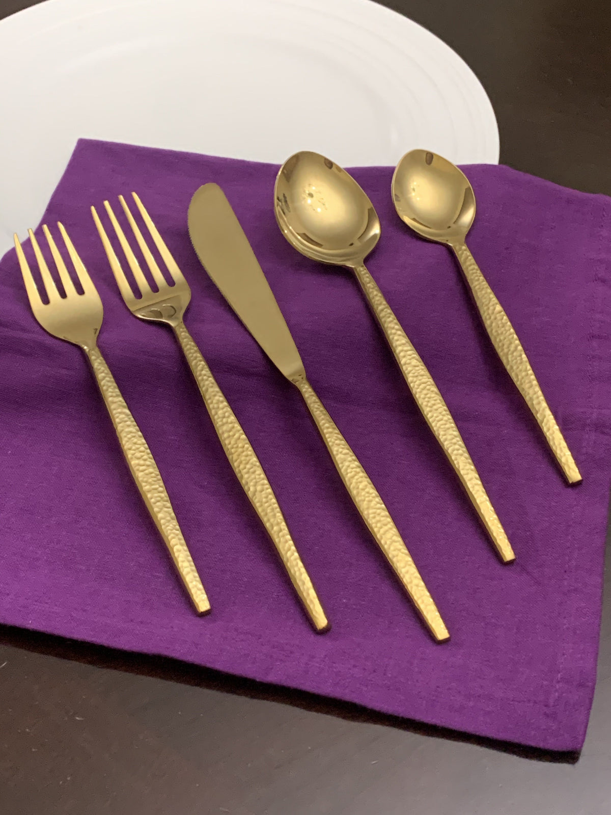 Vibhsa hammered gold flatware set for 4; 5 pieces shown on purple napkin on Tampa Home & Garden Store