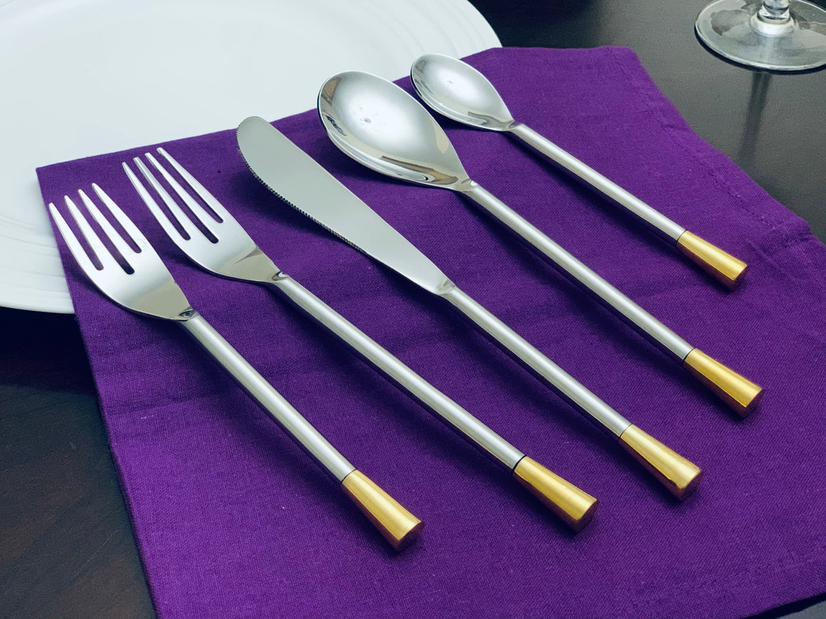 Vibhsa 20-piece silver flatware set for 4 with gold-toned handles on a purple napkin on Tampa Home & Garden Store