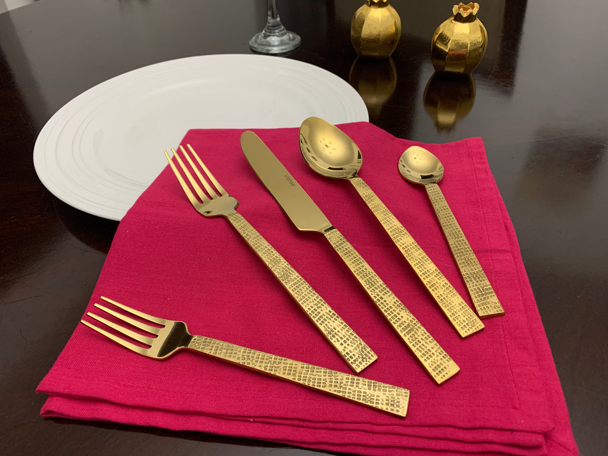 Vibhsa 20-piece gold flatware set Egyptian design displayed on a magenta napkin on Tampa Home & Garden Store