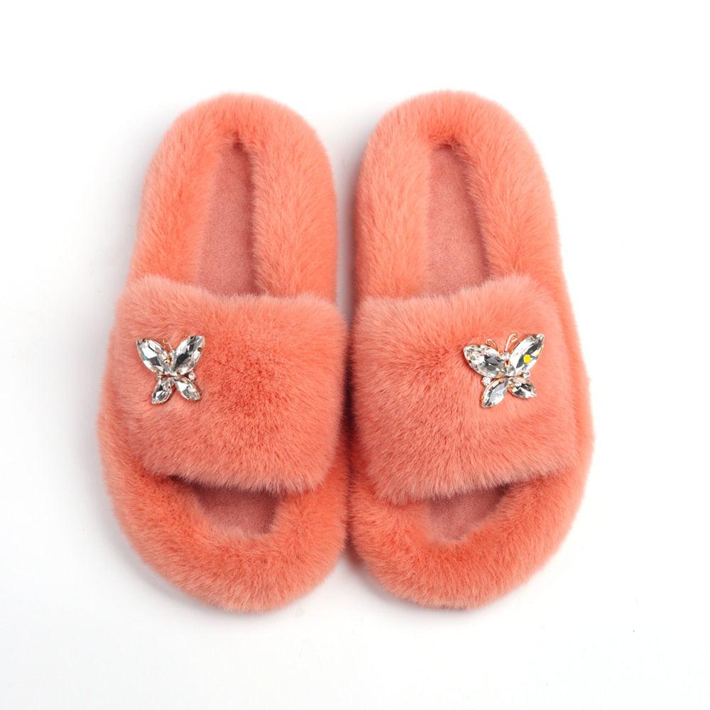 Women’s faux fur slippers coral pink pair from Stevvex with rhinestone butterfly embellishments on the strap on Tampa Home & Garden Store