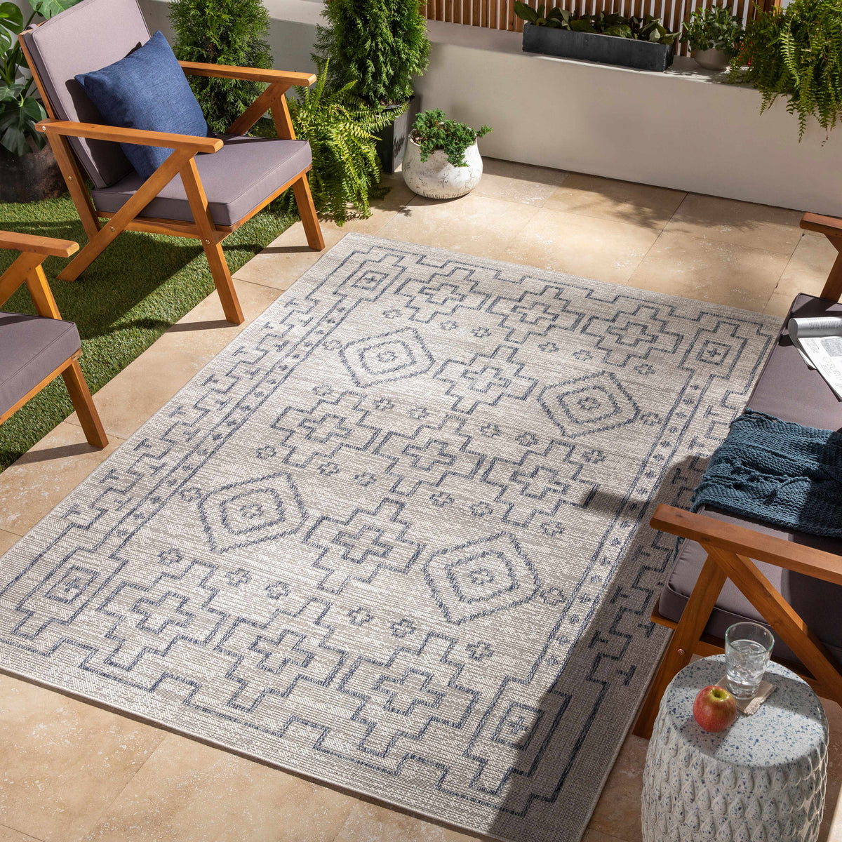 Fernway Indoor Rug Boutique Rugs gray-blue geometric pattern on beige patio with wooden chairs on Tampa Home & Garden Store