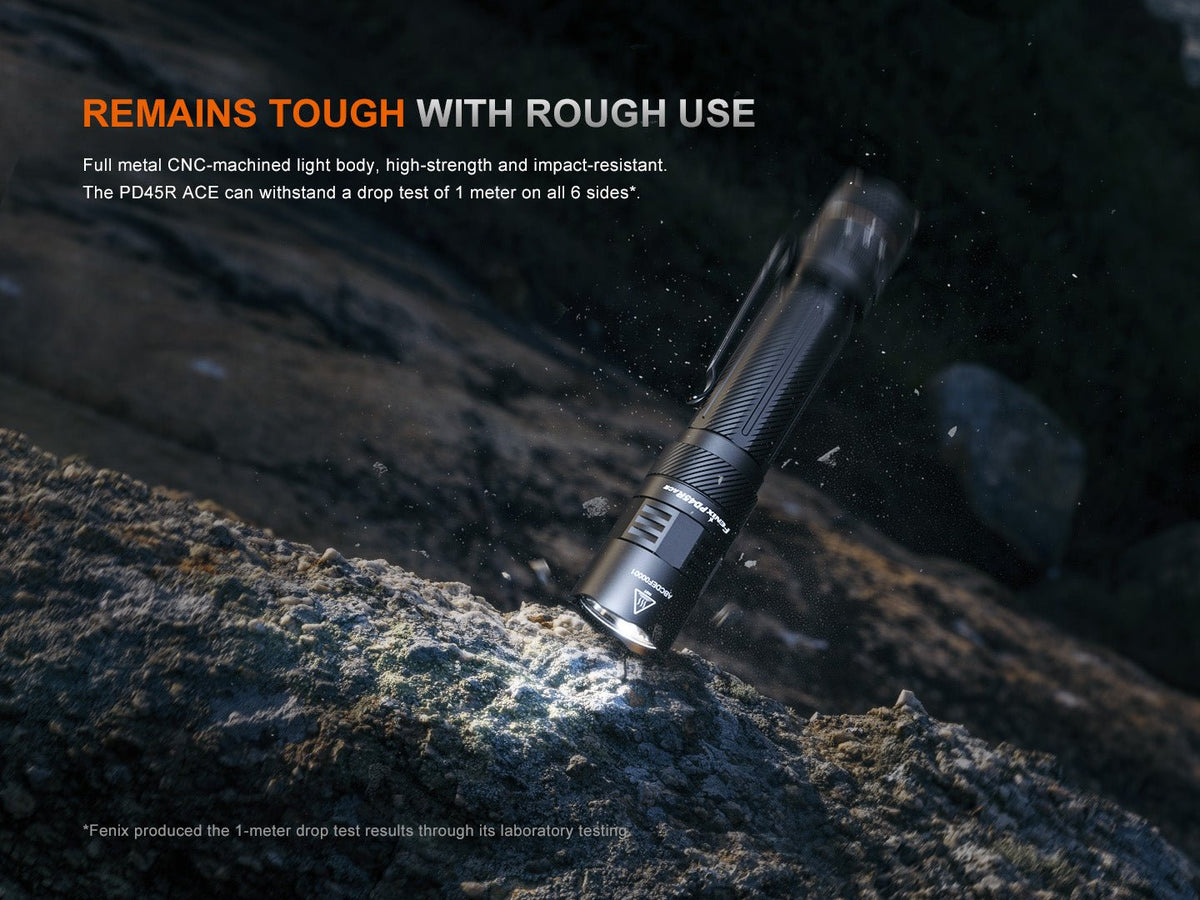 Fenix PD45R ACE tactical flashlight with black CNC-metal body and rugged grip on rocky terrain on Tampa Home & Garden Store