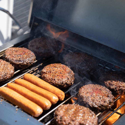 G22 Stainless Tabletop Propane Grill grilling several beef burgers and hot dogs on the grate on Tampa Home & Garden Store