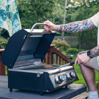 Monument Grills G22 stainless tabletop propane grill with open lid and chrome knobs on Tampa Home & Garden Store