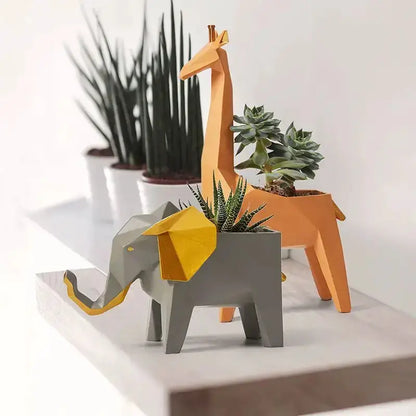 Geometric orange giraffe 3D papercraft planter with succulent, alongside a gray elephant planter on Tampa Home & Garden Store