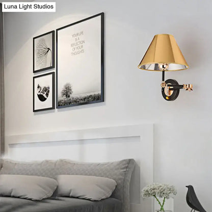 Decorbites gold and black cone wall sconce with brass shade, mounted on a gray bedroom wall on Tampa Home & Garden Store